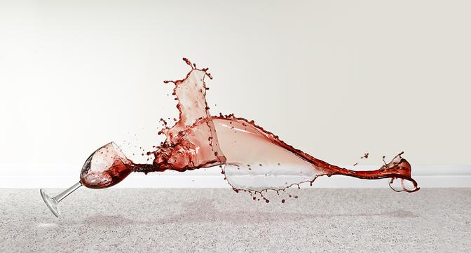 A wine glass has fallen over and spilled its contents onto the floor.
