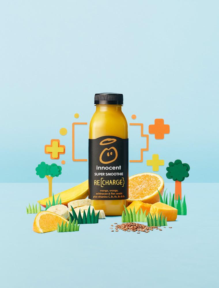A bottle of smoothie with a label featuring a cartoon character, surrounded by various fruits and vegetables.