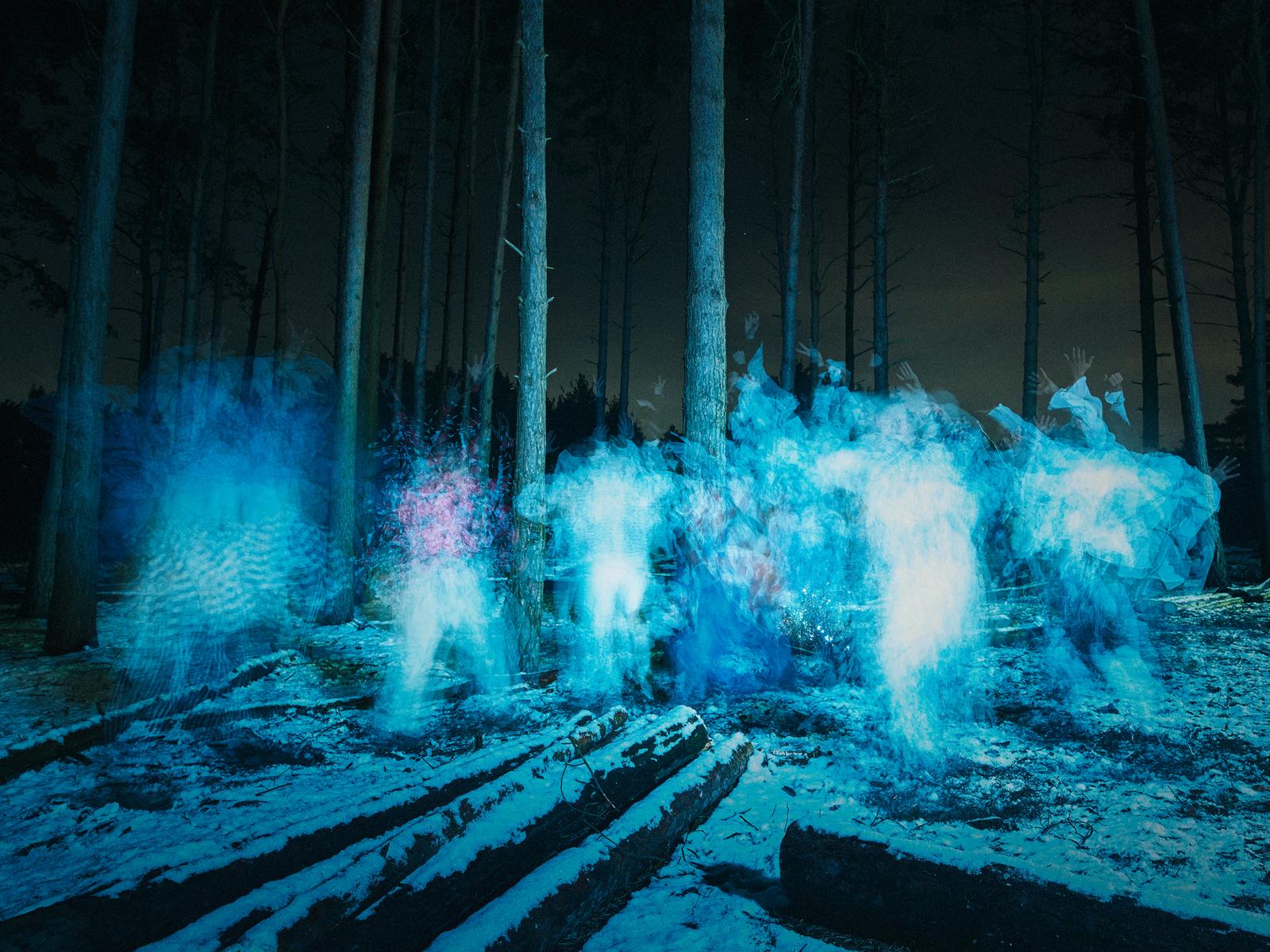 A group of ghostly figures in a forest, surrounded by trees and snow, with a dark and eerie atmosphere.