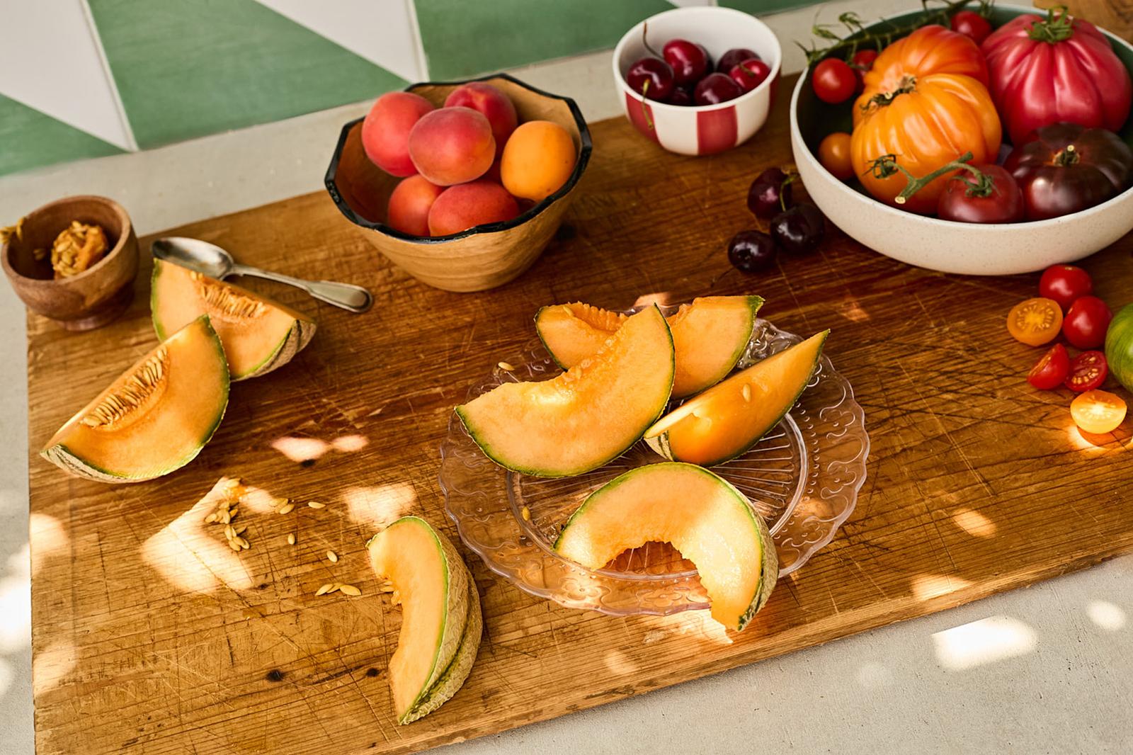 A table filled with fruits, vegetables, and flowers in a garden setting.
