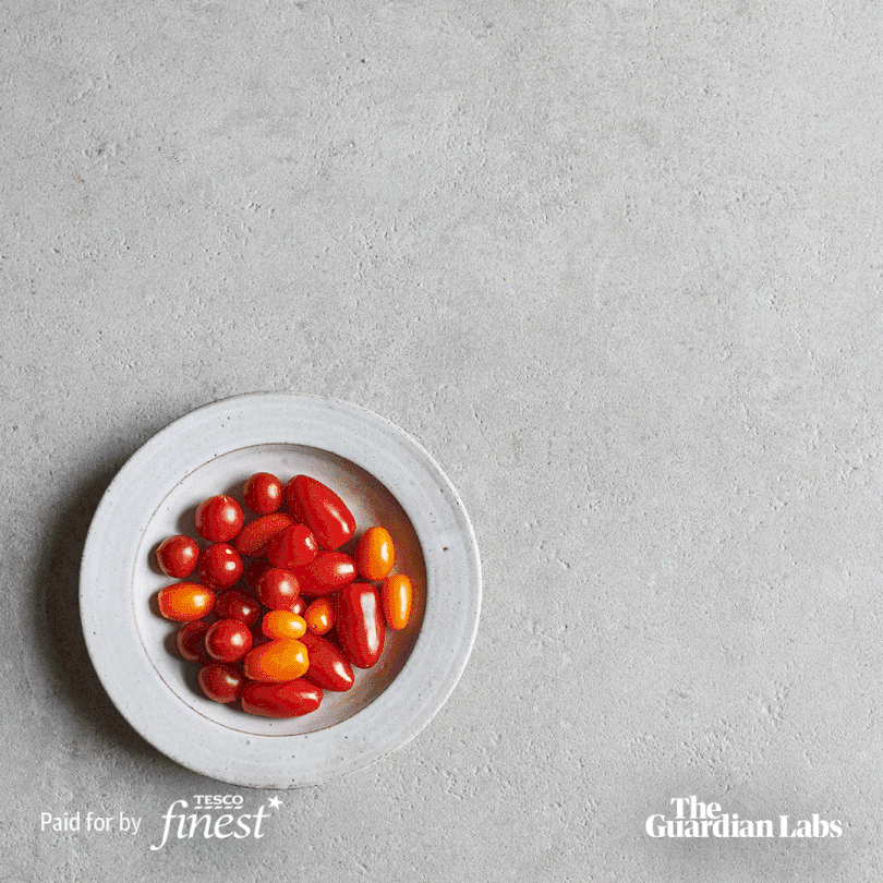 A white ceramic bowl containing a mix of red and orange cherry tomatoes.