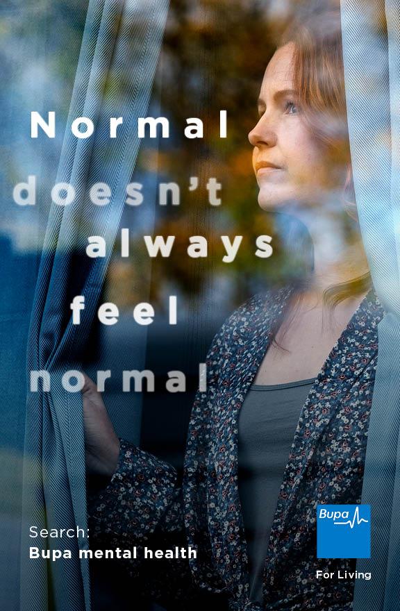 A woman with a concerned expression, looking out of a window with a blurred background, wearing a floral blouse and a cardigan.