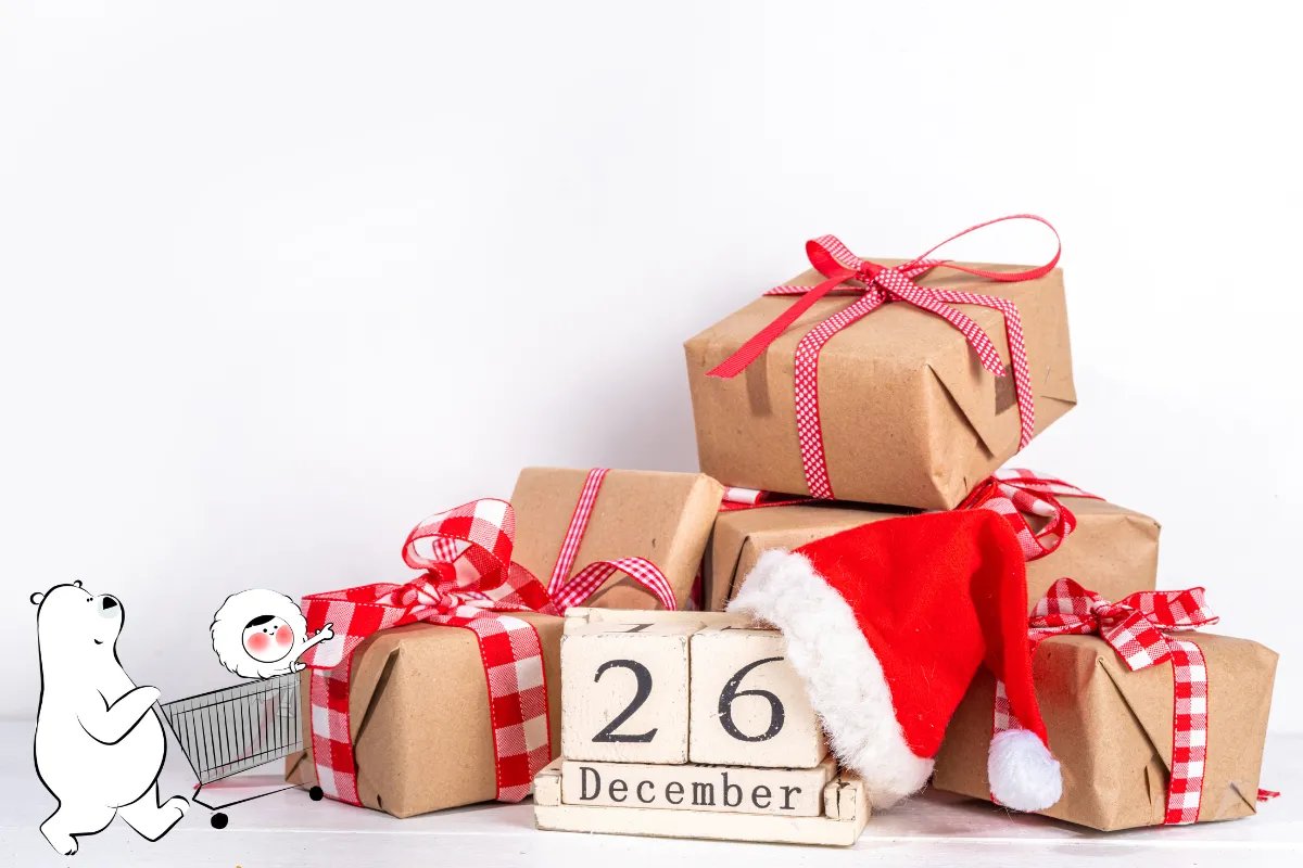 Brown paper–wrapped Christmas gifts with red ribbons stacked beside a wooden block calendar showing 26 December, symbolizing Boxing Day, with a Santa hat resting on top.