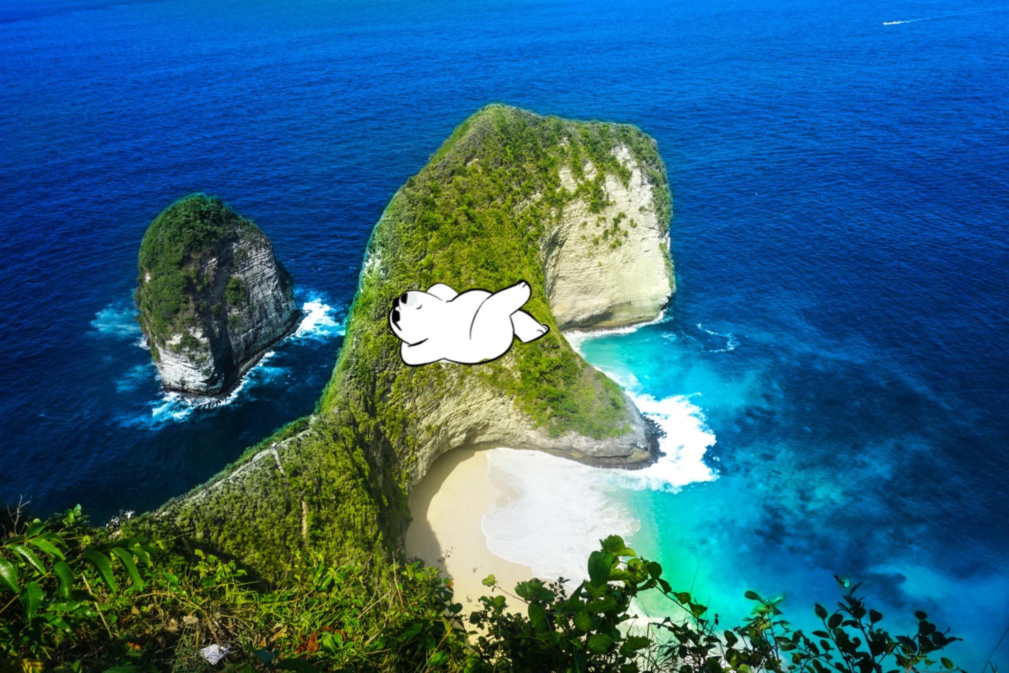 Aerial view of dramatic limestone cliffs and a crescent-shaped white sand beach surrounded by deep blue and turquoise ocean waters at Nusa Penida, Indonesia