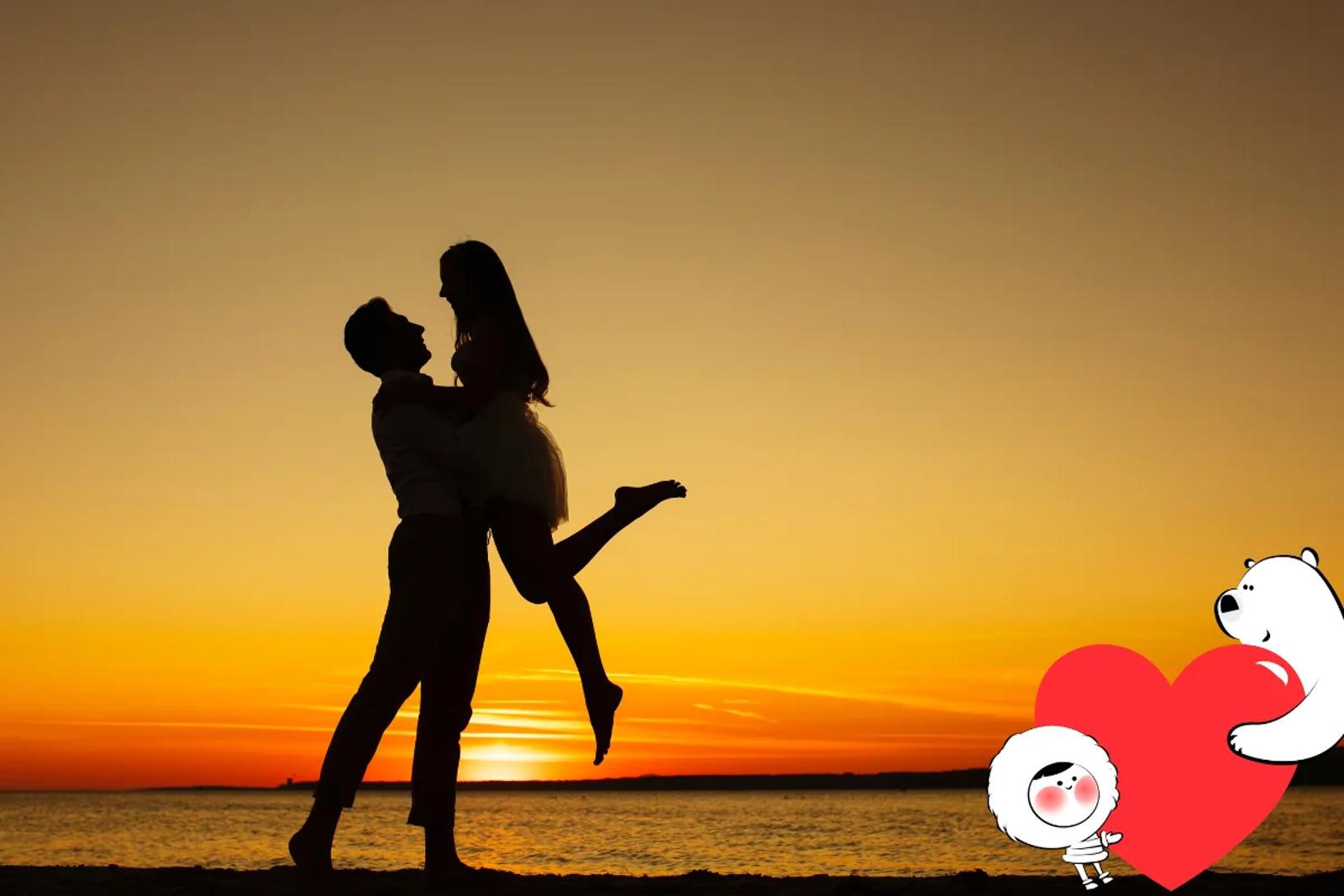 Silhouette of a couple embracing at sunset on a beach, with golden sky reflections over calm water creating a romantic atmosphere.