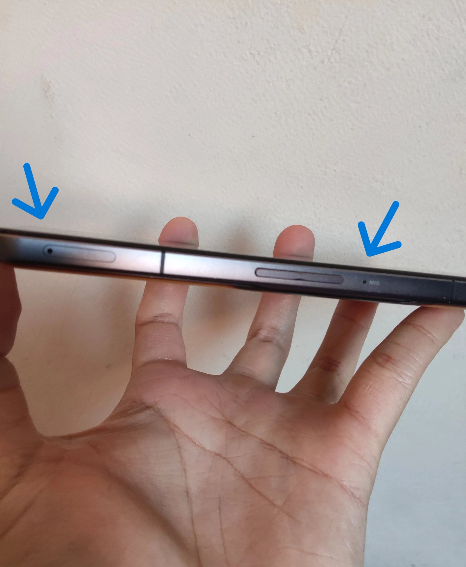 An Android device with its SIM tray and microphone pinholes highlighted