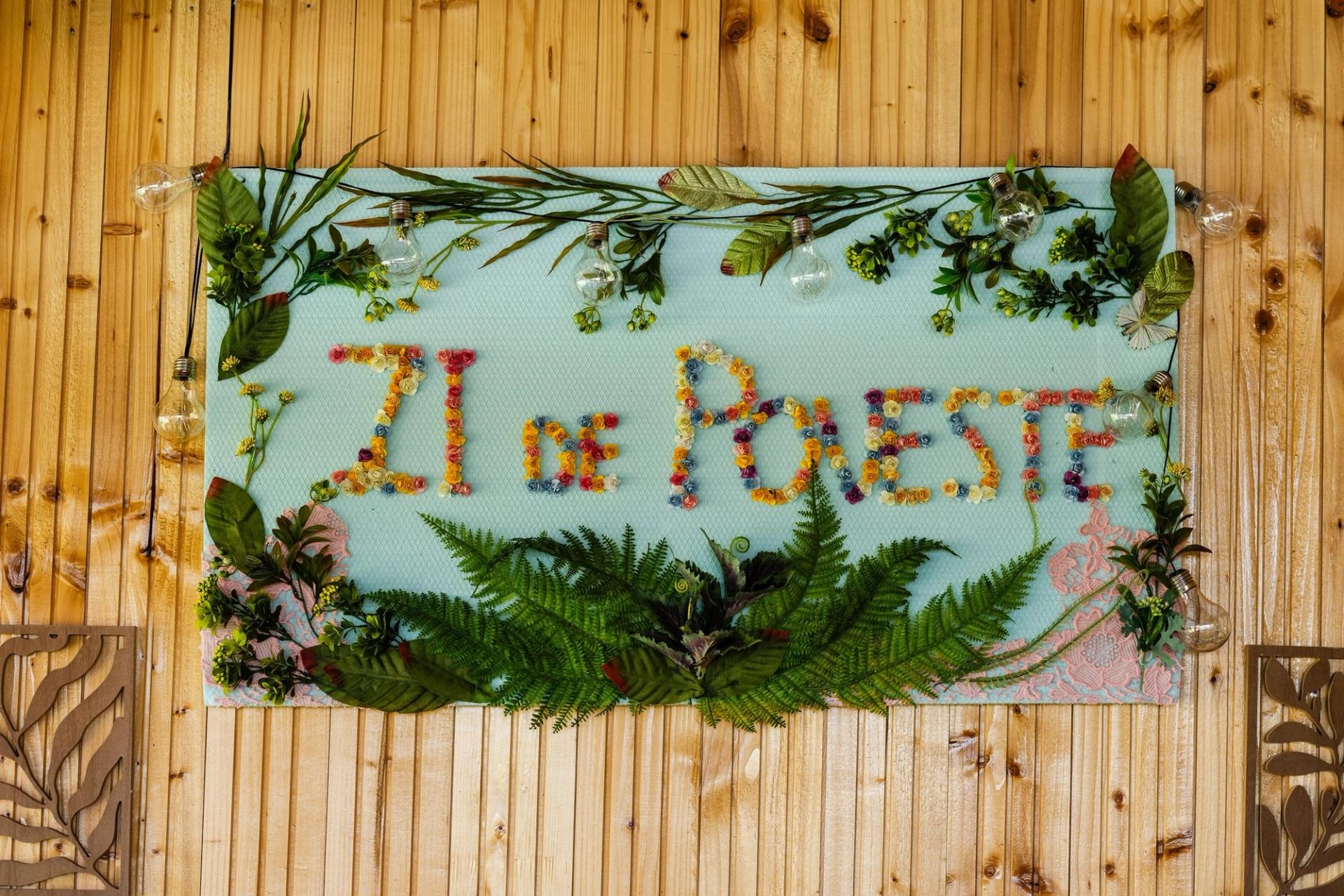 Panou decorativ cu inscripția Zi de Poveste din flori de hârtie, pe peretele de lemn al terasei