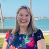 A smiling clinician outdoors with the water behind her