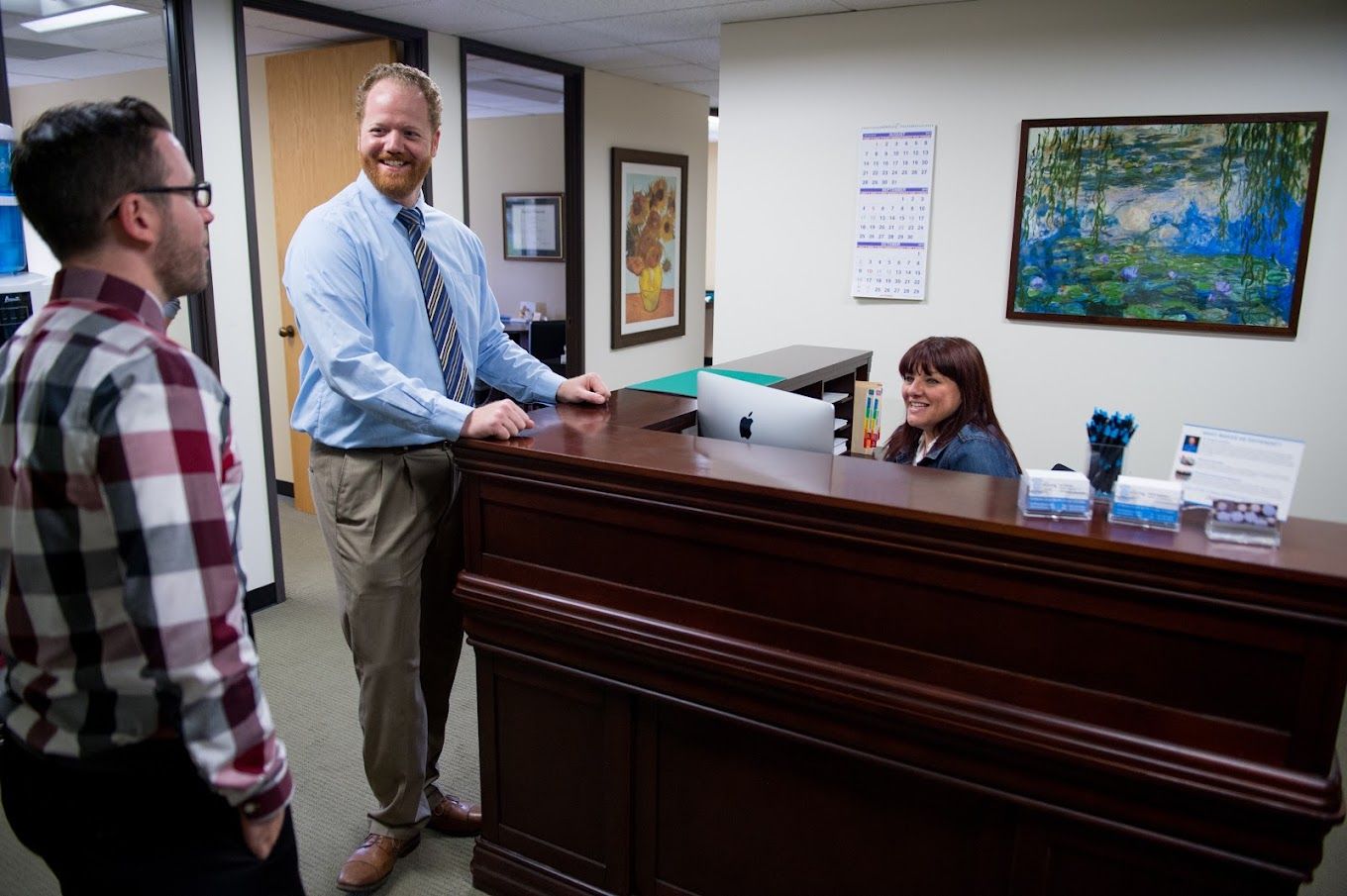 Staff chatting with a visitor at the front desk of The Hearing Clinic