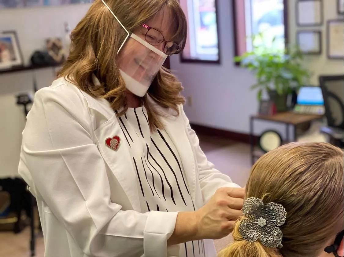 A clinician wearing a face shield examining a patient's ear