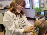 A clinician wearing a face shield examining a patient's ear