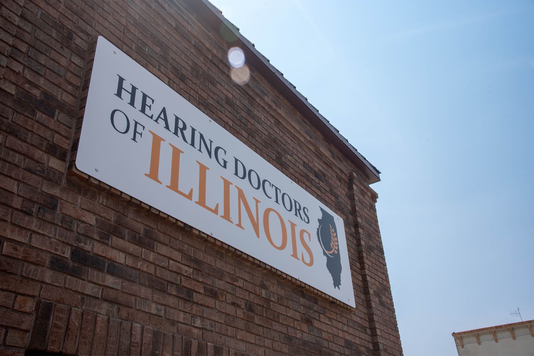 The Hearing Doctors of Illinois sign on the brick wall of the Macomb office
