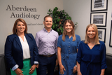 Four members of the Aberdeen Audiology team in front of the practice logo
