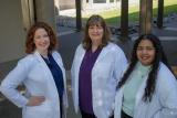 Three clinicians in white coats outside Hearing Specialty Center