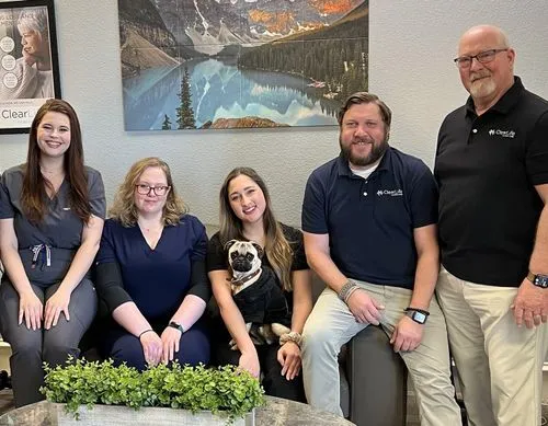 The ClearLife Hearing Care team smiling in their office, one holding a pug