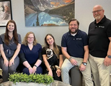The ClearLife Hearing Care team smiling in their office, one holding a pug
