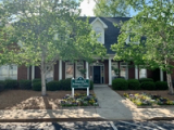 The brick Hearing & Balance Clinic office in Watkinsville with a green sign and flower beds out front