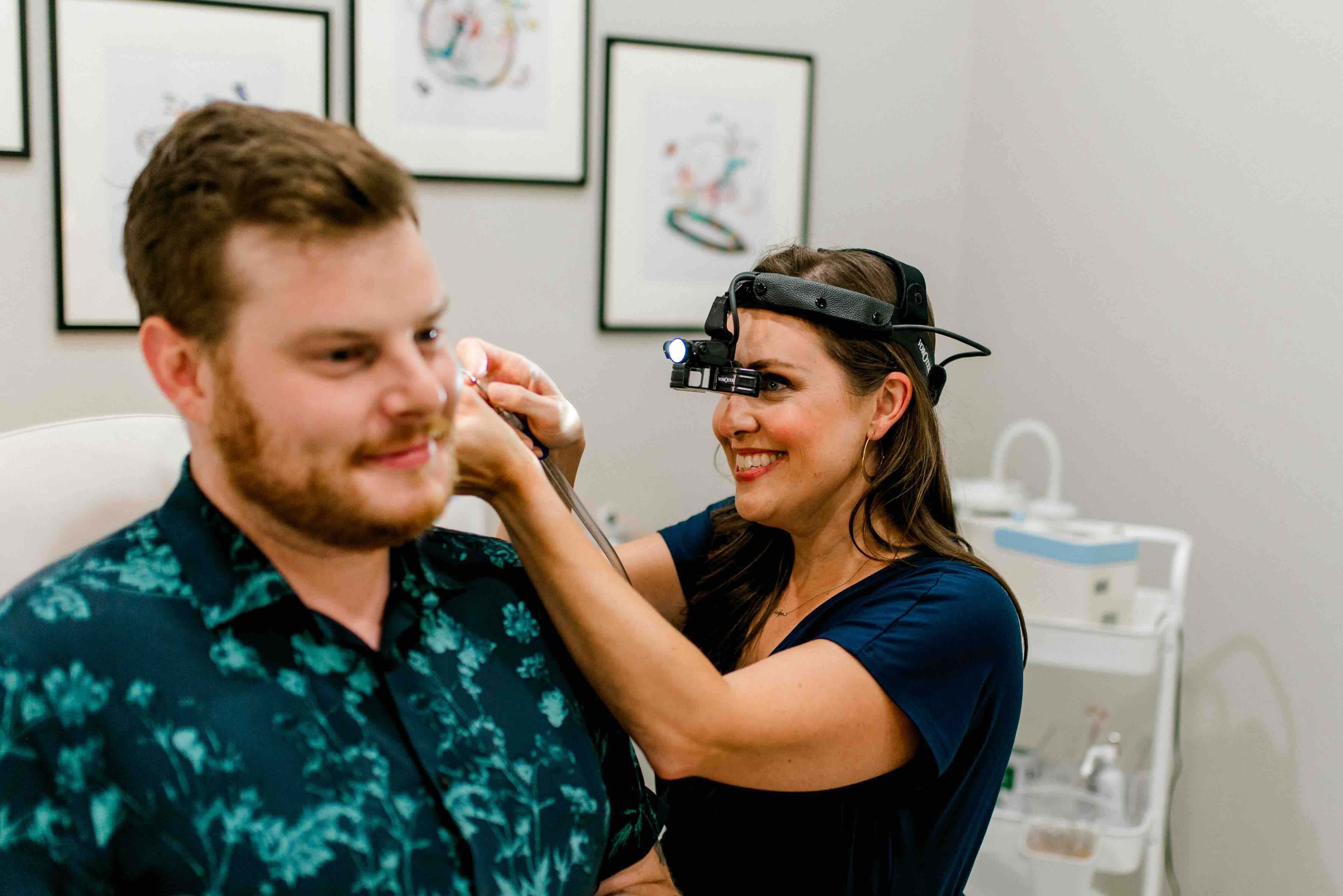 A clinician wearing a head lamp looking into a patient's ear