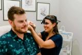 A clinician wearing a head lamp looking into a patient's ear