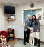 Dr. John Martinetti and a Port Jefferson Hearing team member with a white poodle in the waiting room