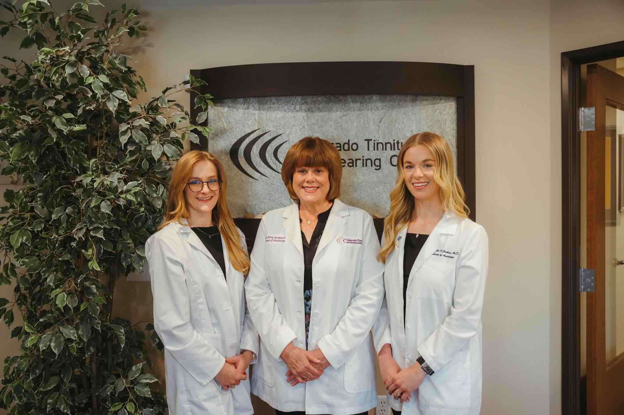 Three clinicians in white coats in the Colorado Tinnitus and Hearing Center lobby