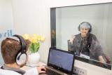 A Live Better Hearing + Balance audiologist running a hearing test with a patient in the sound booth