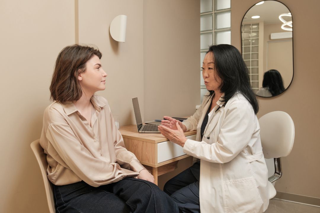 A patient talking with a clinician across a small desk in a calm consulting room