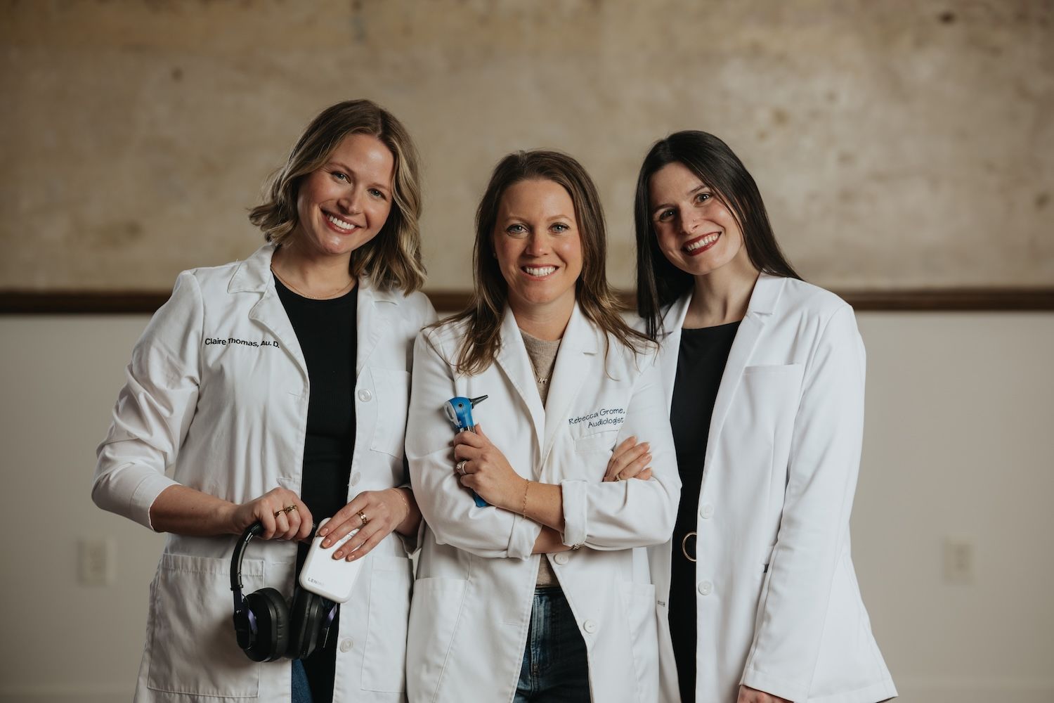 Three Ears4U Hearing Services audiologists in white coats, one holding headphones