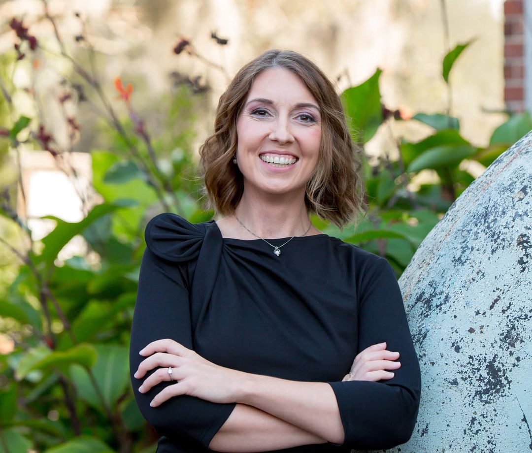 A HearSense audiologist smiling outdoors among green plants