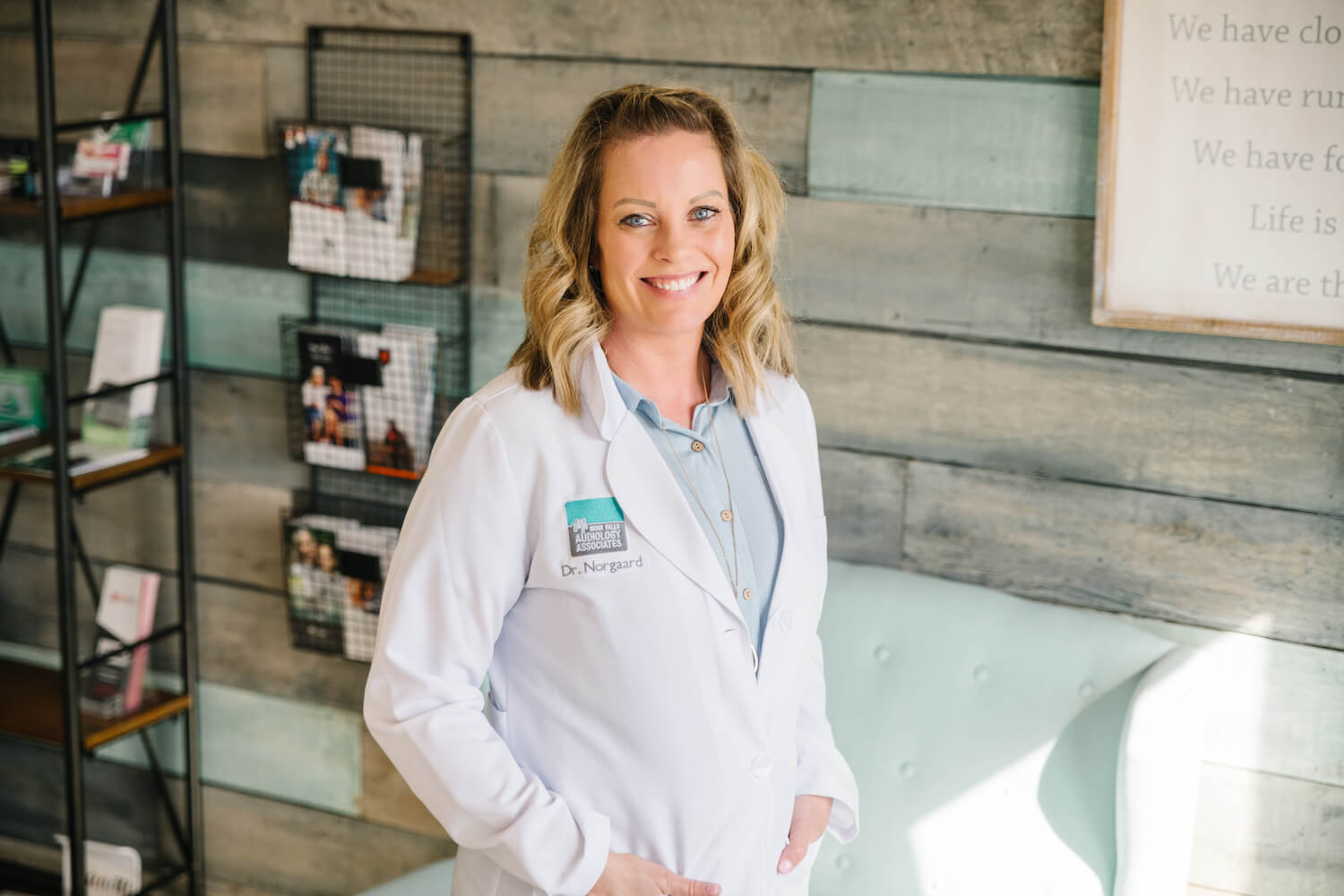 A smiling audiologist in a white coat in the Sioux Falls Audiology Associates office