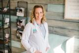 A smiling audiologist in a white coat in the Sioux Falls Audiology Associates office