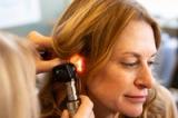 An audiologist at Audiologic Solutions checking a patient’s ear with an otoscope