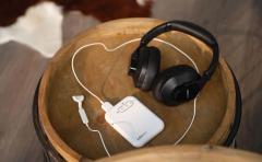 The Lenire device on a wooden tabletop: headphones, a white handheld controller and a small tongue piece