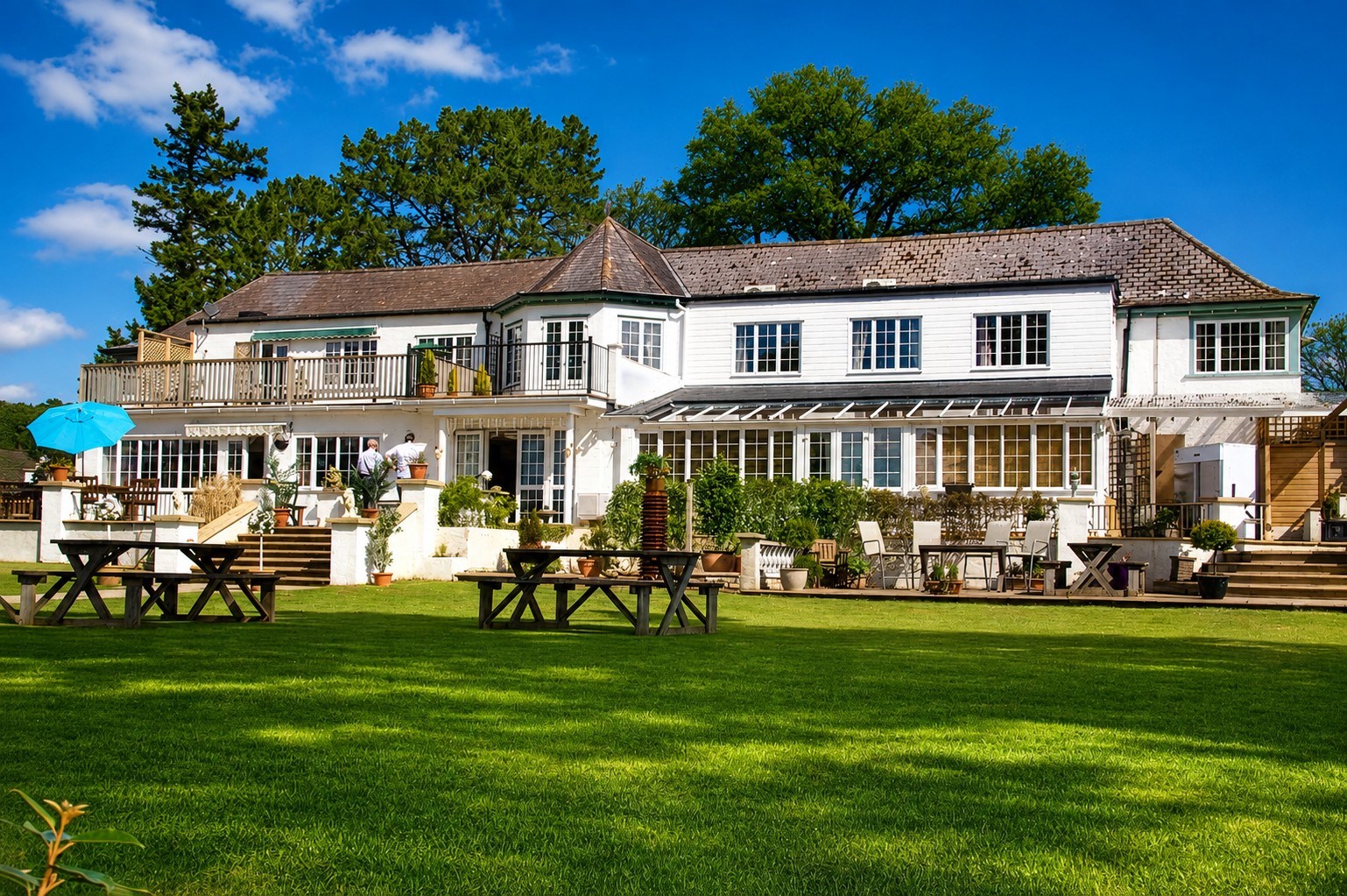 Large country house with outdoor seating overlooking a spacious lawn