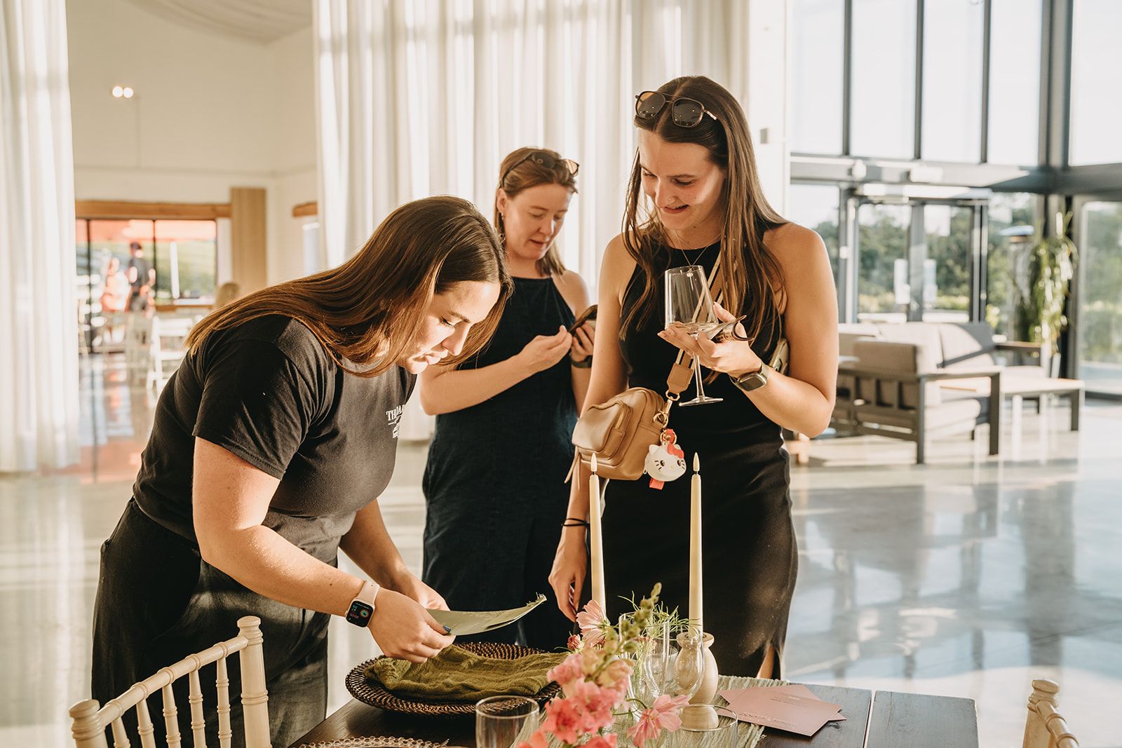 Event staff and guests arranging table settings at a bright venue