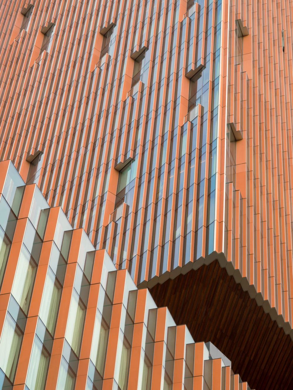 Orange ribbed cladding and projecting details wrapping a building corner