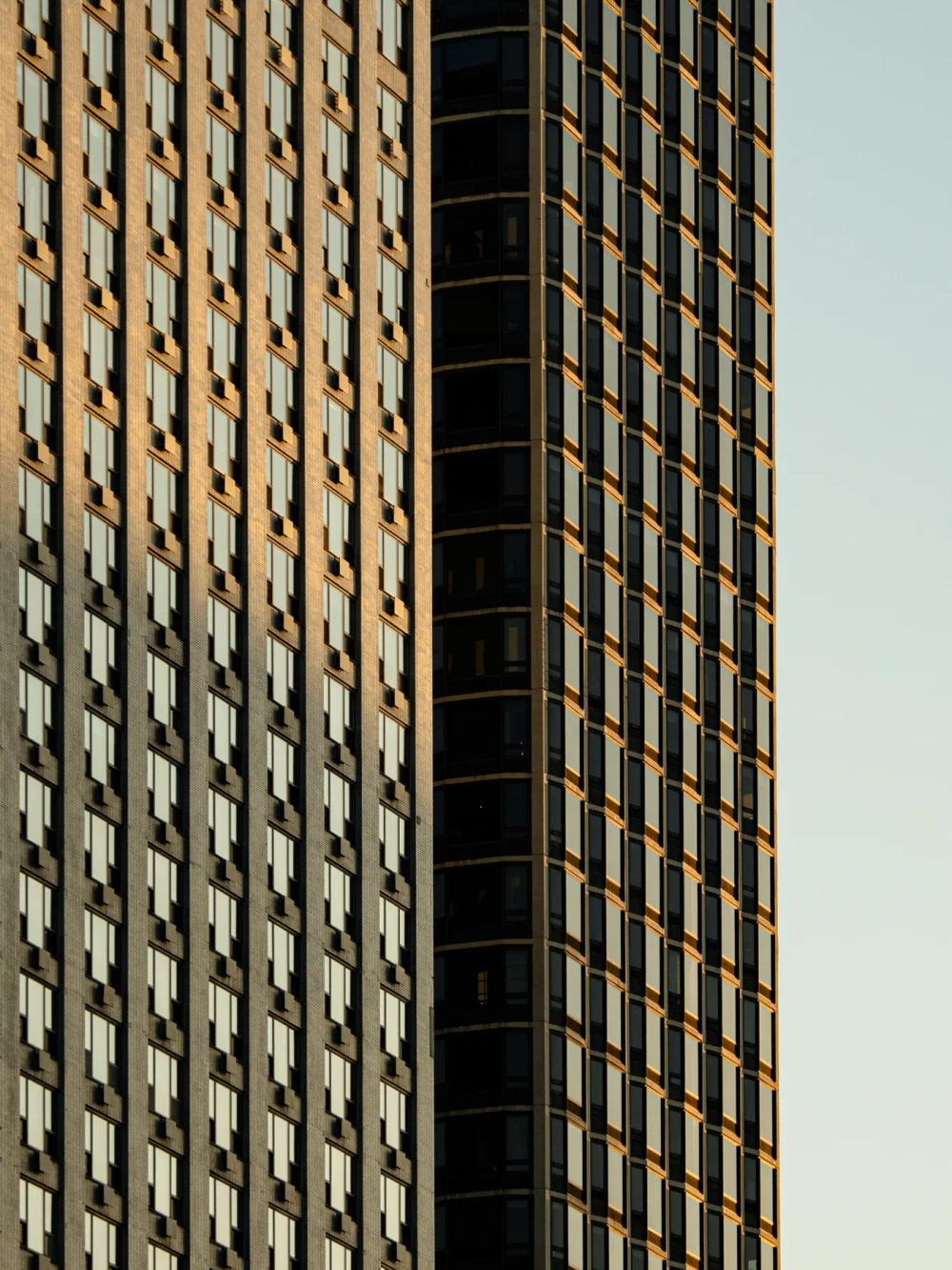 Warm sunlight grazing repeated vertical fins and windows on a tower