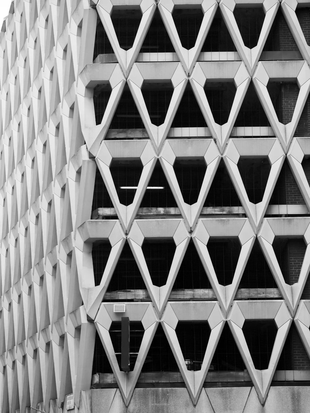 A close view of a concrete facade with repeated diamond-shaped openings