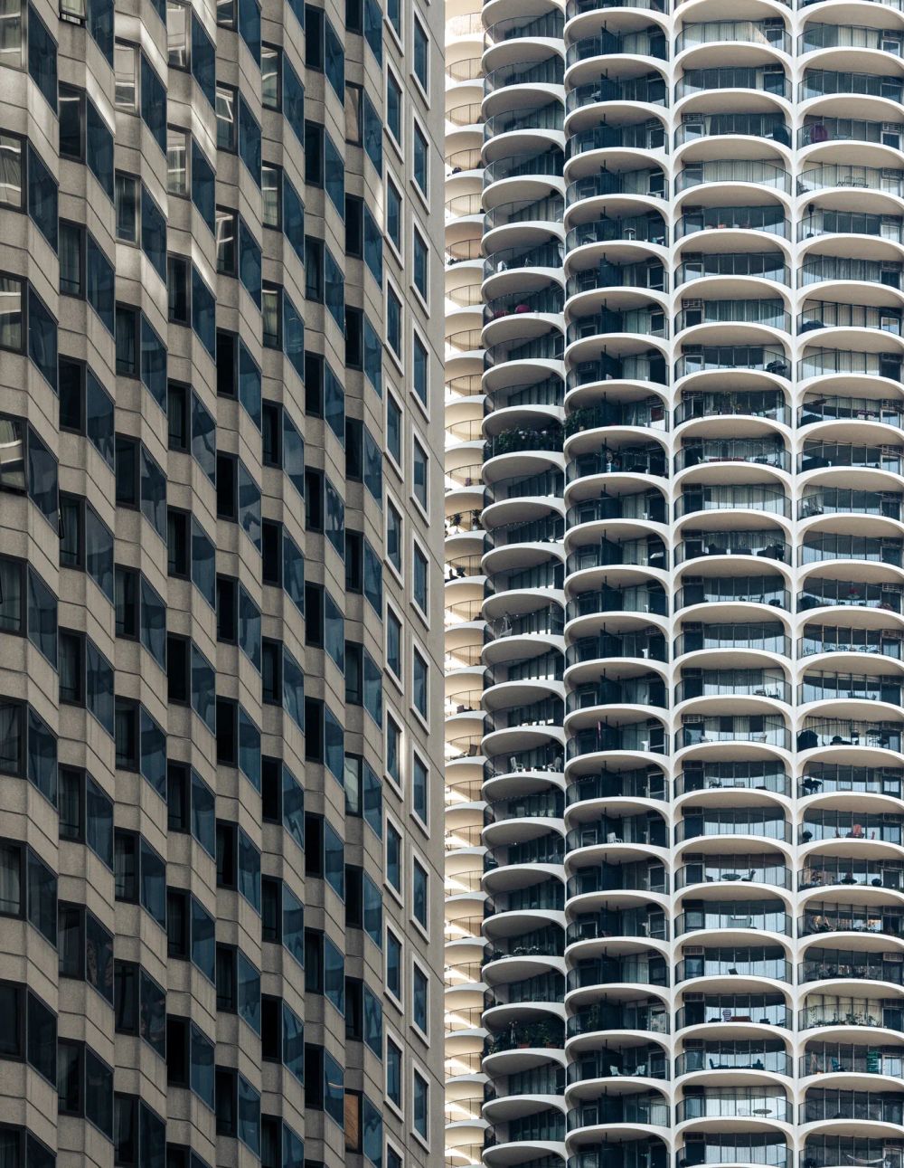 A rectilinear facade beside the rounded balconies of a neighboring tower