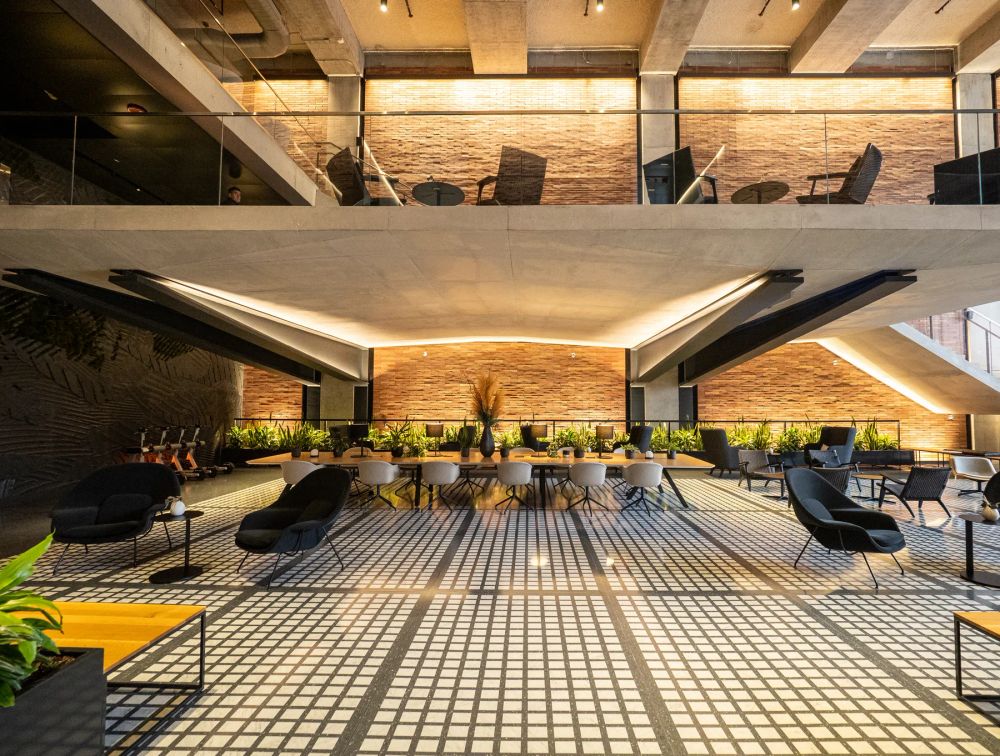 A brick and steel atrium with seating and a grid of sunlight across the floor