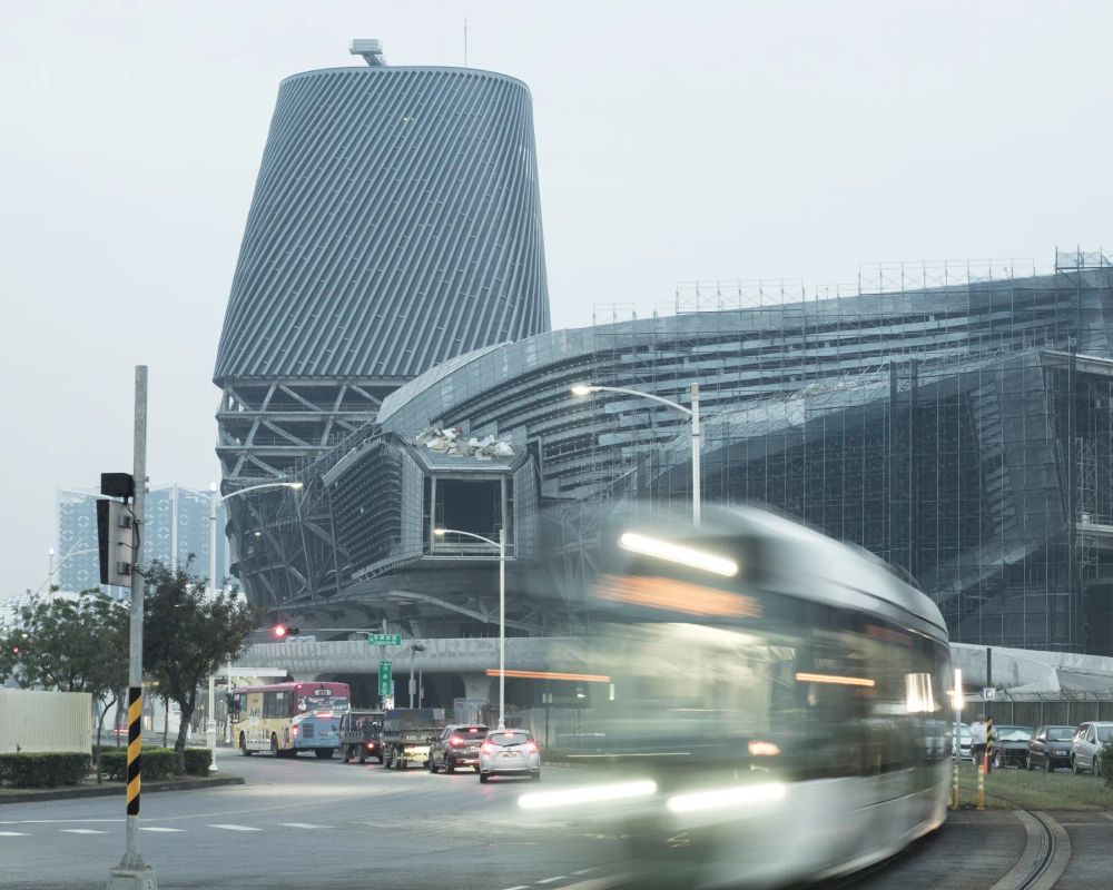A blurred tram curving past a contemporary building