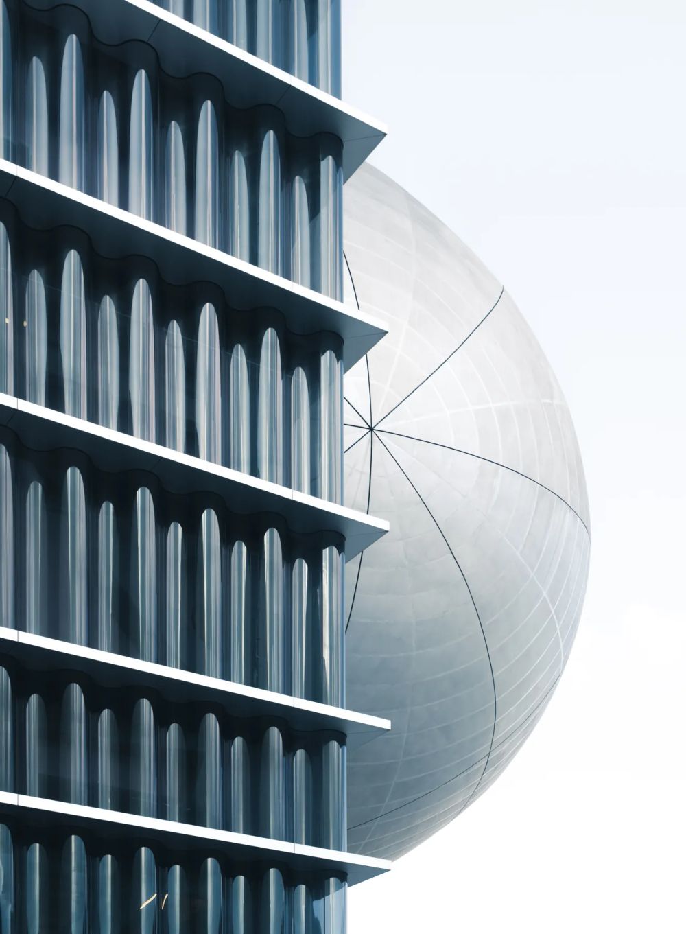 Dark vertical facade fins beside a curved silver building surface