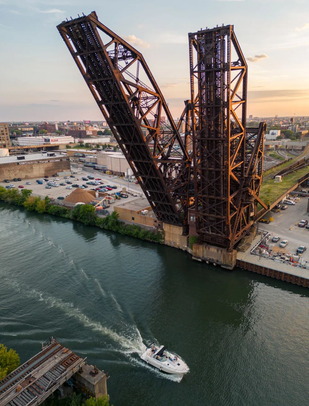 An aerial view of a raised steel railway bridge beside a boat on the river