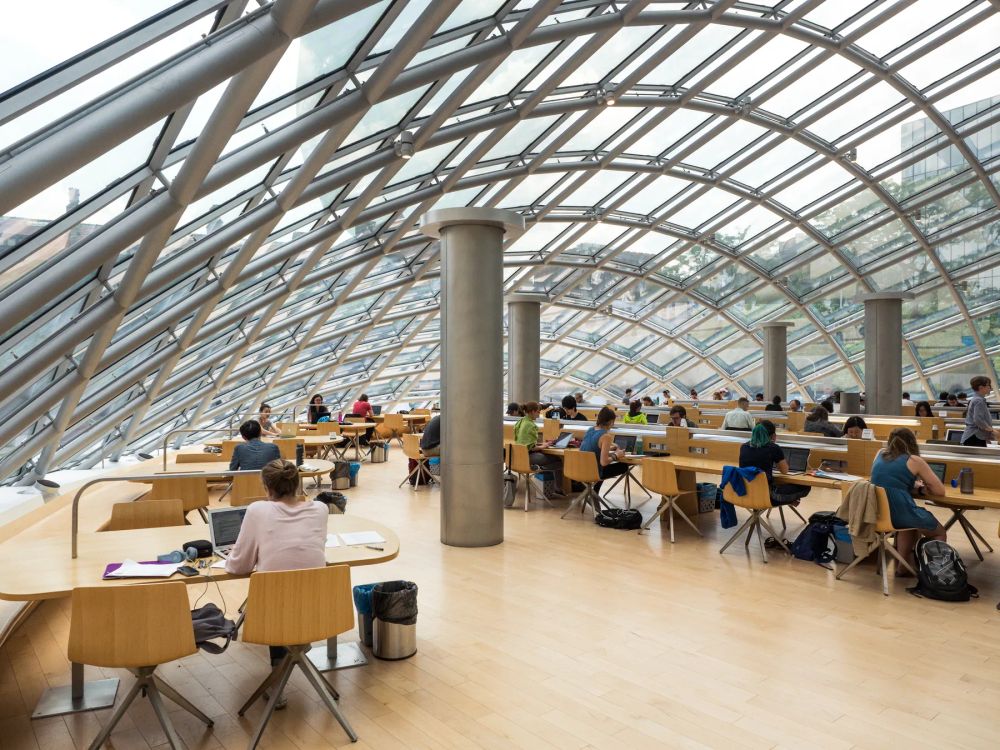 People studying at desks beneath a sloping glass roof