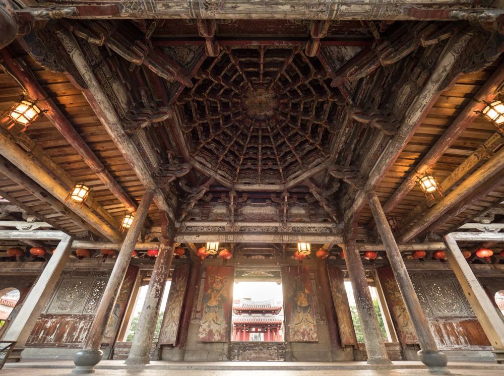 An ornate timber canopy supported by stone columns in a historic interior