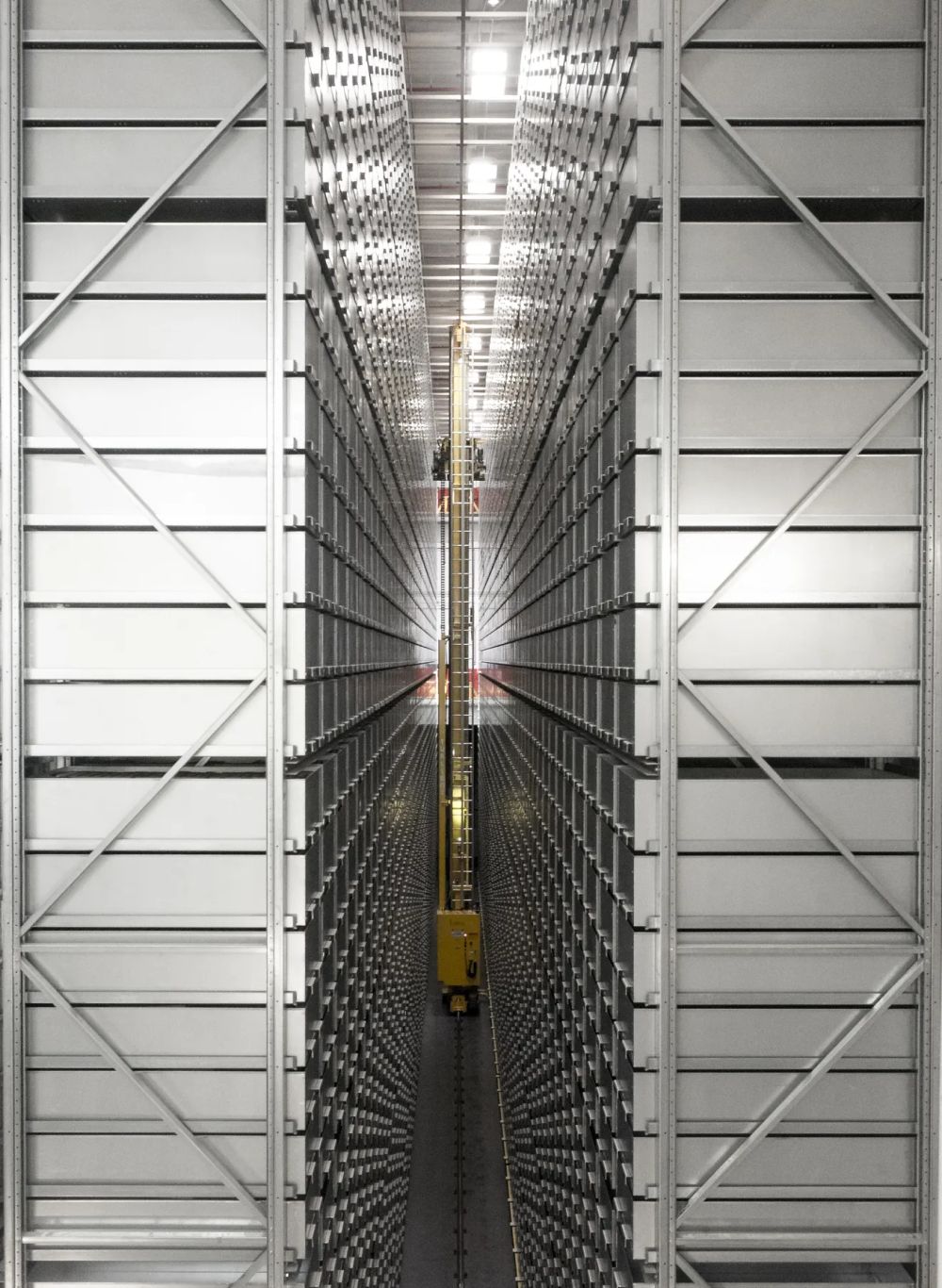 A tall industrial storage aisle with symmetrical structural bracing