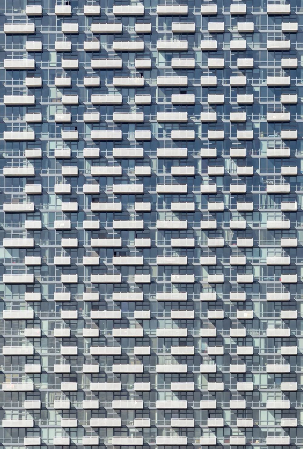 Staggered projecting window frames forming a dense pattern across a high-rise facade
