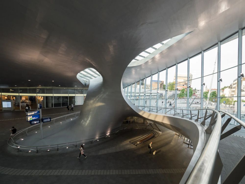 People moving through a curving metallic transit hall