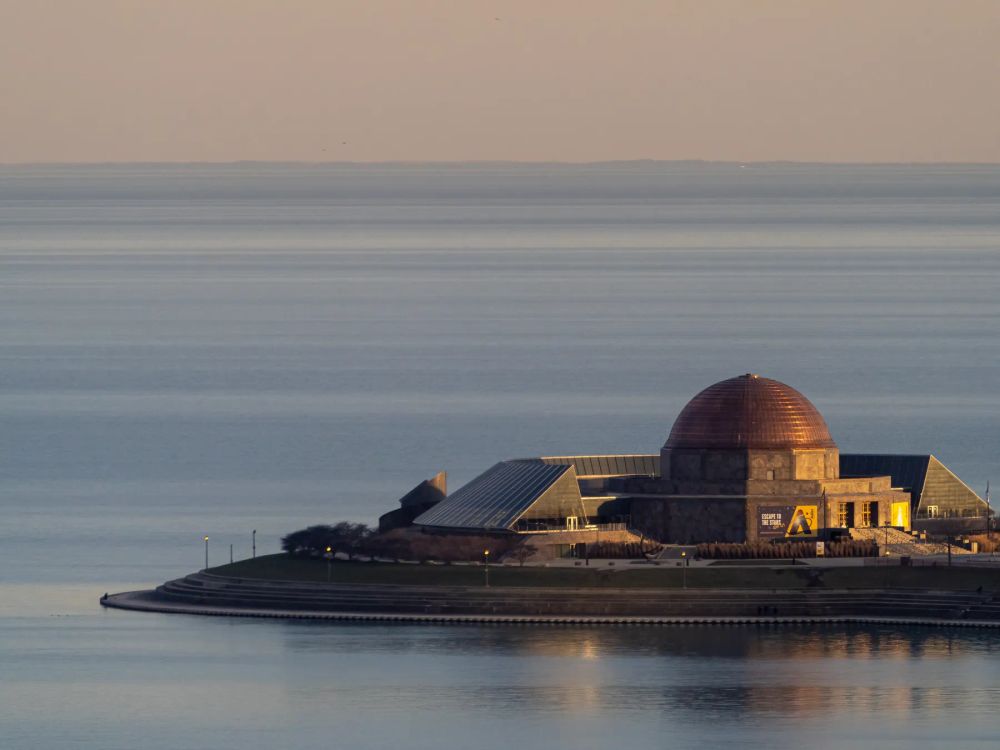 A domed waterfront building beside softly blurred water under a muted evening sky