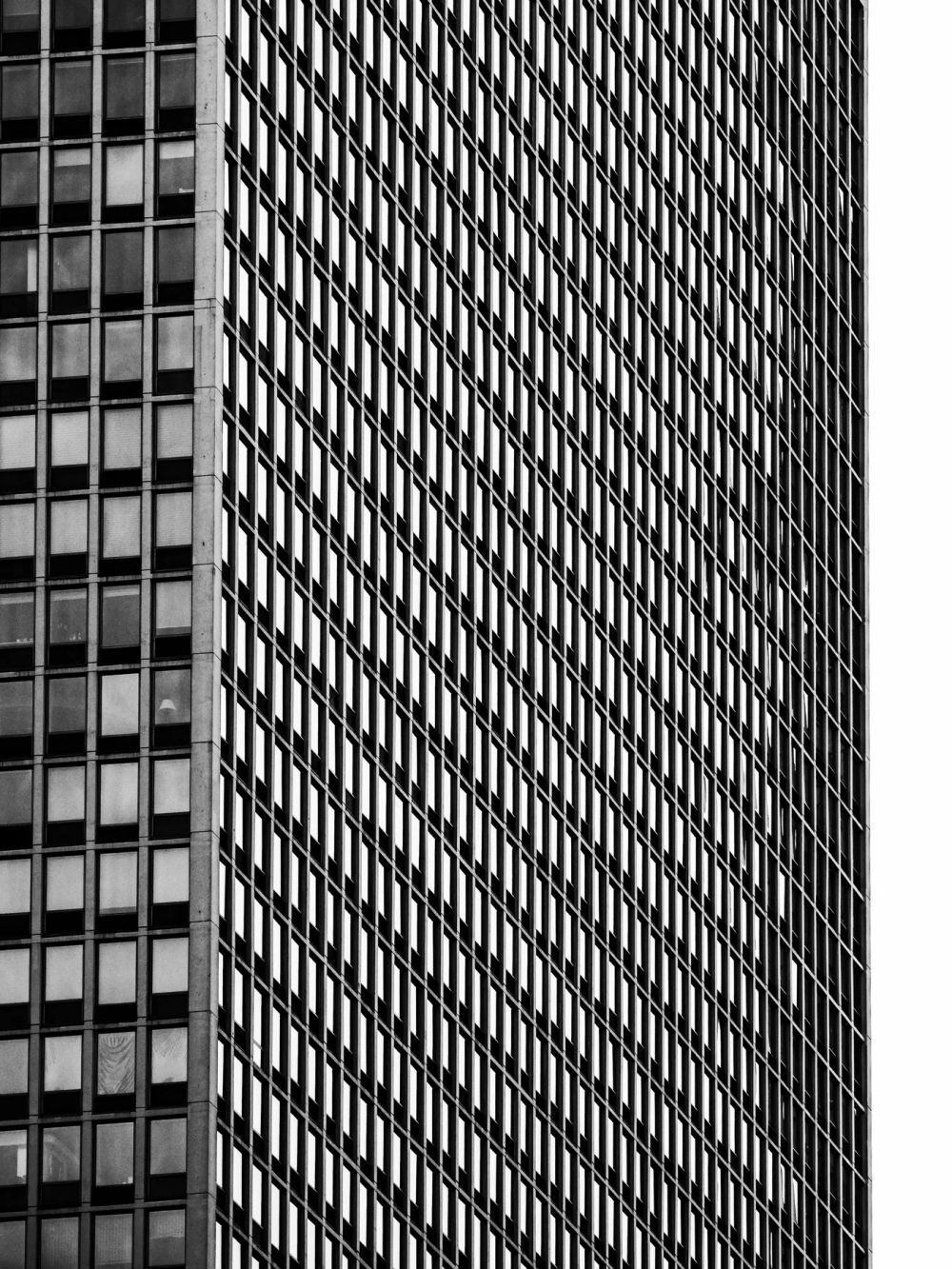 Two high-rise window grids meeting at an angle in black and white